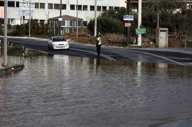 Ένας τροχονόμος ρυθμίζει την κυκλοφορία σε έναν πλημμυρισμένο δρόμο στο Μαρκόπουλο, 27 Νοεμβρίου 2016. Αρκετά προβλήματα προκάλεσε στην Αττική η έντονη βροχόπτωση που σημειώθηκε τα ξημερώματα. Η Πυροσβεστική έχει δεχθεί έως αυτή την ώρα 200 κλήσεις για αντλήσεις υδάτων από οικίες και 8 για απεγκλωβισμούς ατόμων, ενώ τώρα επιχειρούν σε διάφορες περιοχές της Αττικής (Κυψέλη, Πατήσια, Ψυχικό, Παιανία, Δυτικά προάστια) 45 πυροσβέστες με 20 οχήματα. ΑΠΕ-ΜΠΕ/ΑΠΕ-ΜΠΕ/ΓΙΑΝΝΗΣ ΚΟΛΕΣΙΔΗΣ